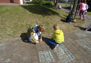 chłopcy grają w kółko i krzyżyk na chodniku kredą